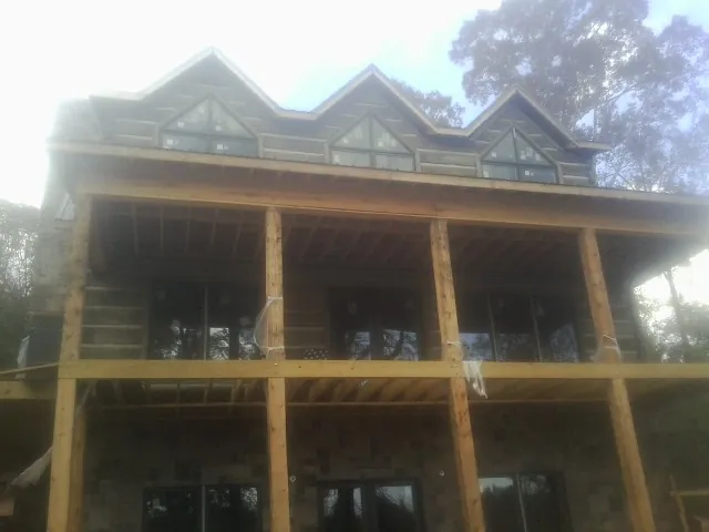 Dormers and porch framing on a large log home under construction — Roof Coating work by our crew in Rockland