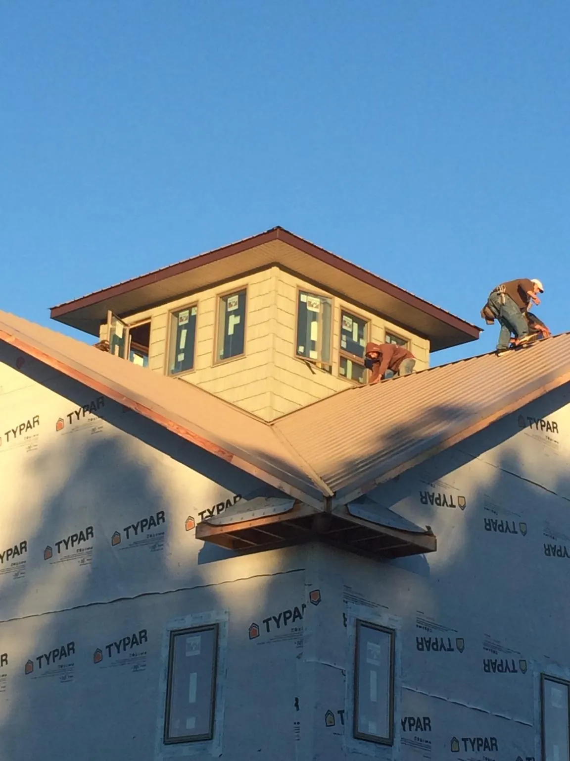 Roofers working around a rooftop cupola on a new metal roof at sunset — Roof Waterproofing in Rockland by Roofing Brothers